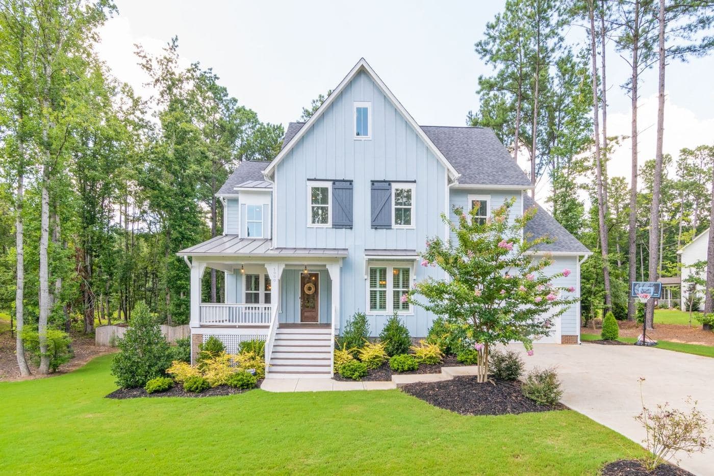 White farmhouse-style home with a covered porch on a wooded lot