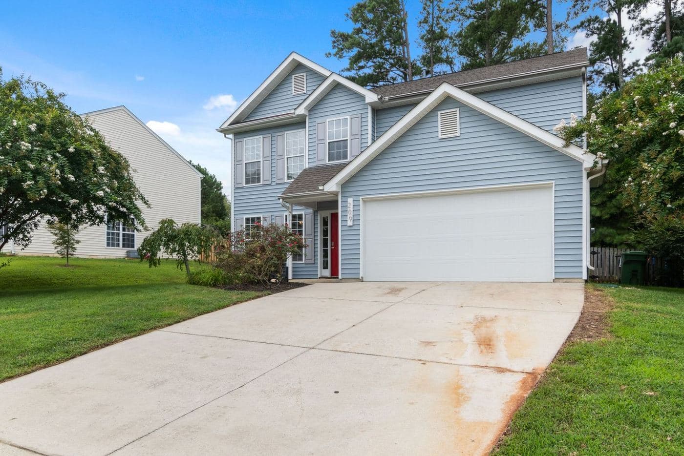 Light-gray two-story home with a front-facing garage and a mature lawn